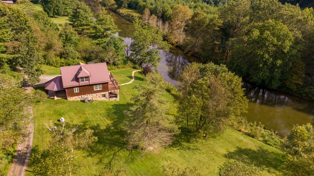 A peaceful riverside scene featuring a house nestled among trees, with the river running in the foreground. This image emphasizes the area’s tranquility and easy access to outdoor activities like fishing, hiking, and picnicking.